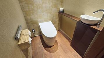 A small, modern bathroom with a toilet, sink, and wooden cabinet.
