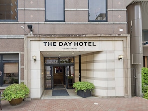 A hotel entrance with a sign reading 'THE DAY HOTEL ShinYokohama.'