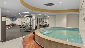 Un gimnasio con piscina, equipo de ejercicio y una terraza de madera.