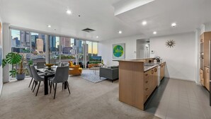 Un apartamento moderno con comedor, cocina y amplios ventanales con vistas a la ciudad.