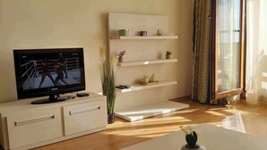 A modern living room with a flat-screen TV, a white console table, a coffee table, and a minimalist shelving unit. - Apartment mit 2 Schlafzimmern in Obzor - 6 Pools & Bio- See (Obzor)