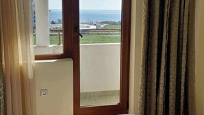 A bedroom with a bed, a window with a view of the sea, and a curtain. - Apartment mit 2 Schlafzimmern in Obzor - 6 Pools & Bio- See (Obzor)