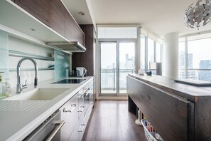 Une cuisine moderne dotée d’une grande fenêtre, d’un four encastré et d’un plan de travail en bois.