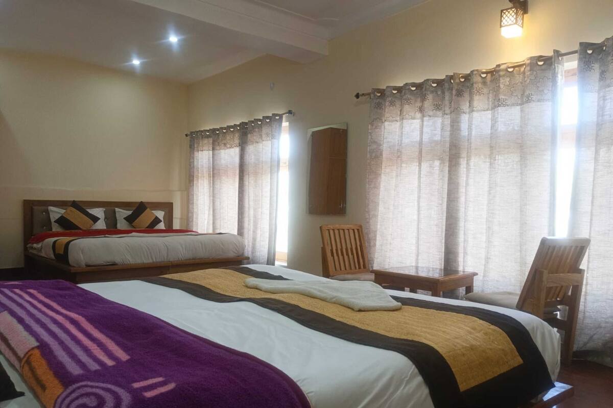 A hotel room with a large bed, a wooden headboard, a small table, two chairs, and a mirror on the wall.