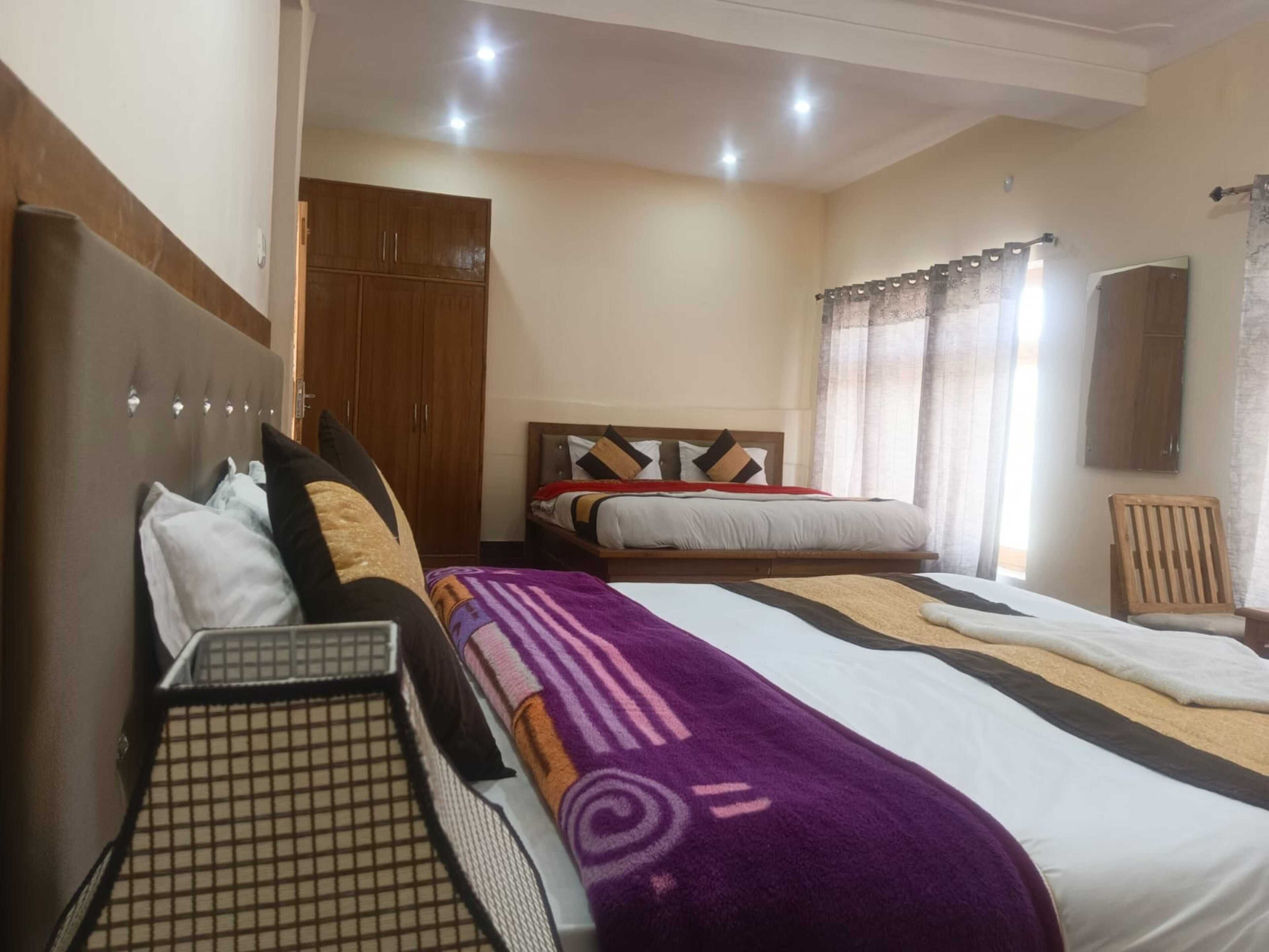 A hotel room with two beds, a wardrobe, a chair, and a window with curtains.