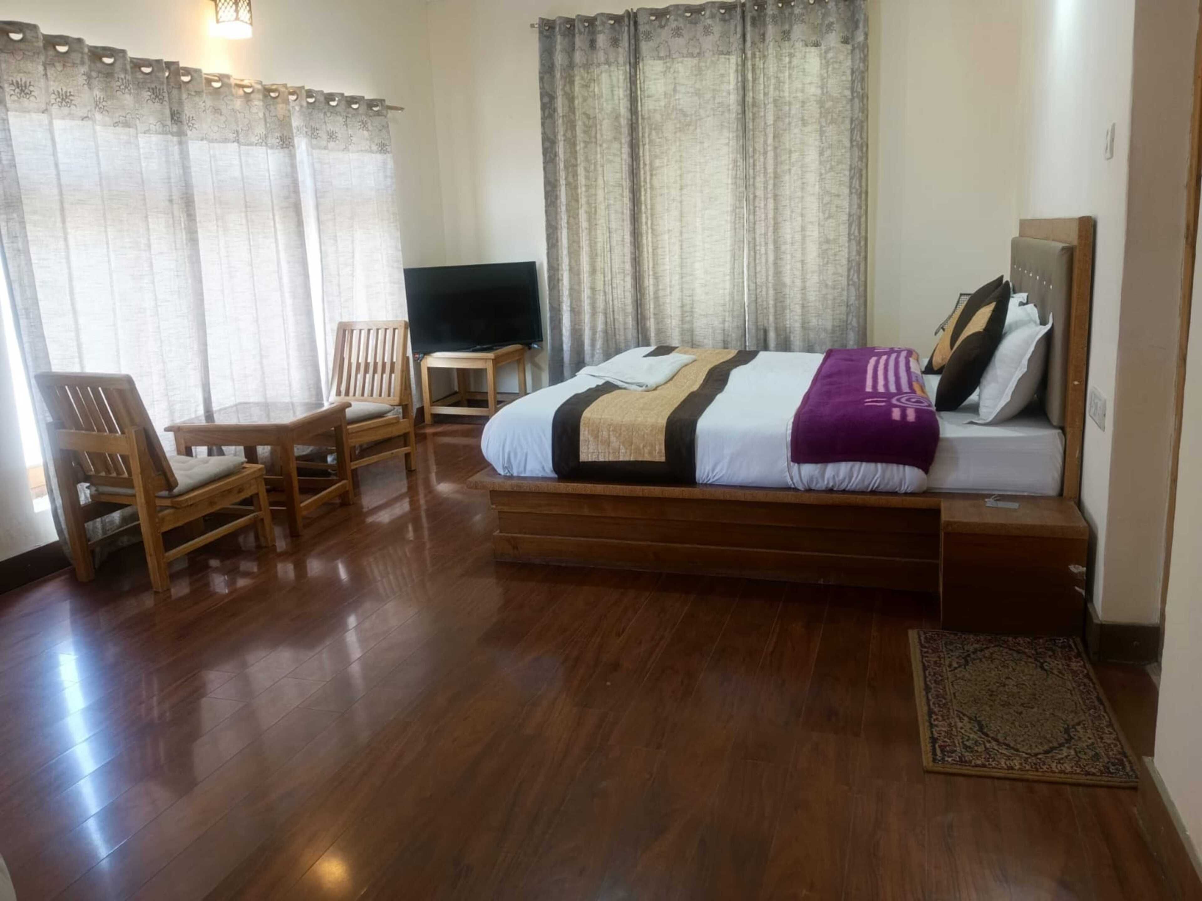 Quarto com cama, televisão, escrivaninha e cadeira.