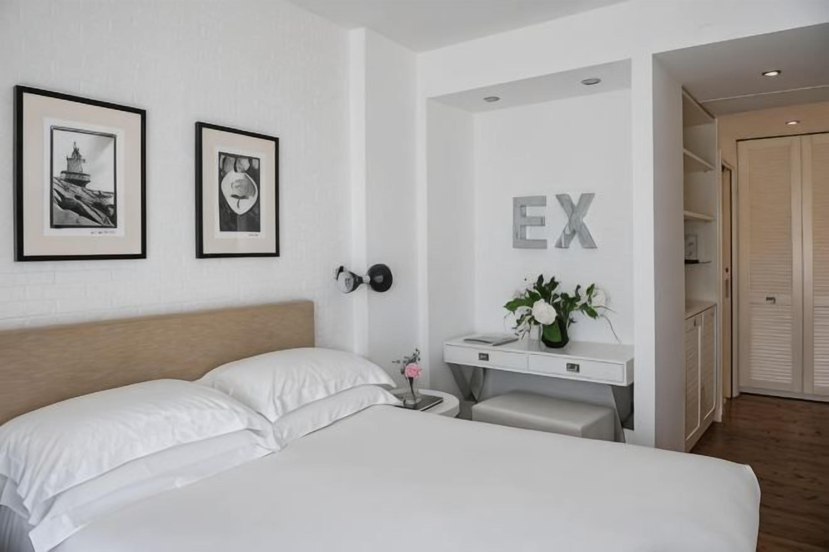 Ein Hotelzimmer mit Bett, Nachttisch, Schreibtisch und Kleiderschrank.