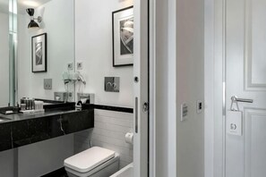 A modern bathroom with a black countertop, white toilet, and a large mirror. - Excelsior Hotel, Spa & Lido (Pesaro)