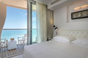 A hotel room with a bed, a small table with fruit, a chair, and a balcony with a view of the sea. - Excelsior Hotel, Spa & Lido (Pesaro)