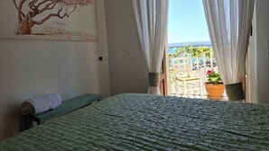 Un dormitorio con cama, un banco, un cuadro y vistas al exterior.