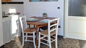 Una cocina con una mesa de comedor, sillas, un cuadro y un armario.
