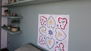 Una habitación con una cama, una pared decorada con recortes de papel y estanterías con plantas en macetas.