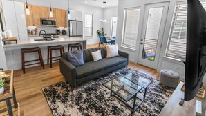 A modern living space with a kitchen, dining area, and seating area. - Private Gated Townhome Near Med Center & NRG (Houston)