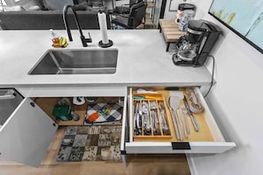 Una cocina moderna con un lavaplatos integrado, una cafetera y un cajón con utensilios.