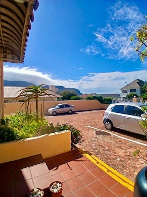 Um bairro residencial com calçada pavimentada, carros estacionados e vista para montanhas ao longe.