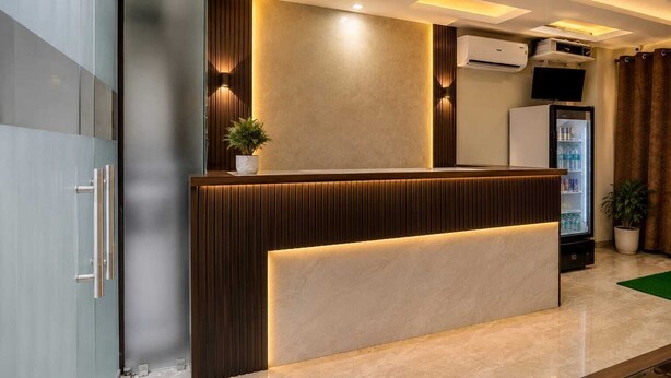 A reception desk with a modern design, a potted plant, and a refrigerator. - Hotel shad residency (Patna)
