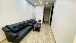 A hallway with a black leather sofa and a small table with a bottle and glass. - Hotel shad residency (Patna)