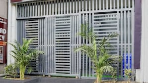 A building facade with a large metal gate, small potted plants, and a staircase leading to the entrance. - Hotel shad residency (Patna)