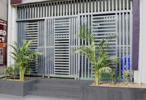 A building facade with a large metal gate, small potted plants, and a staircase leading to the entrance. - Hotel shad residency (Patna)