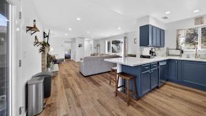 Una cocina moderna con una isla central, suelo de madera y armarios azules.