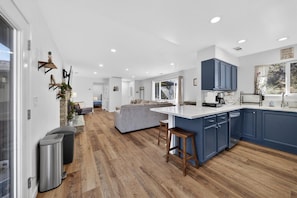 A modern kitchen with a central island, wooden flooring, and blue cabinets. - Escape to peaceful OAK HAVEN, near Yosemite/Bass Lake + Patio + Firepit + Games (Oakhurst)