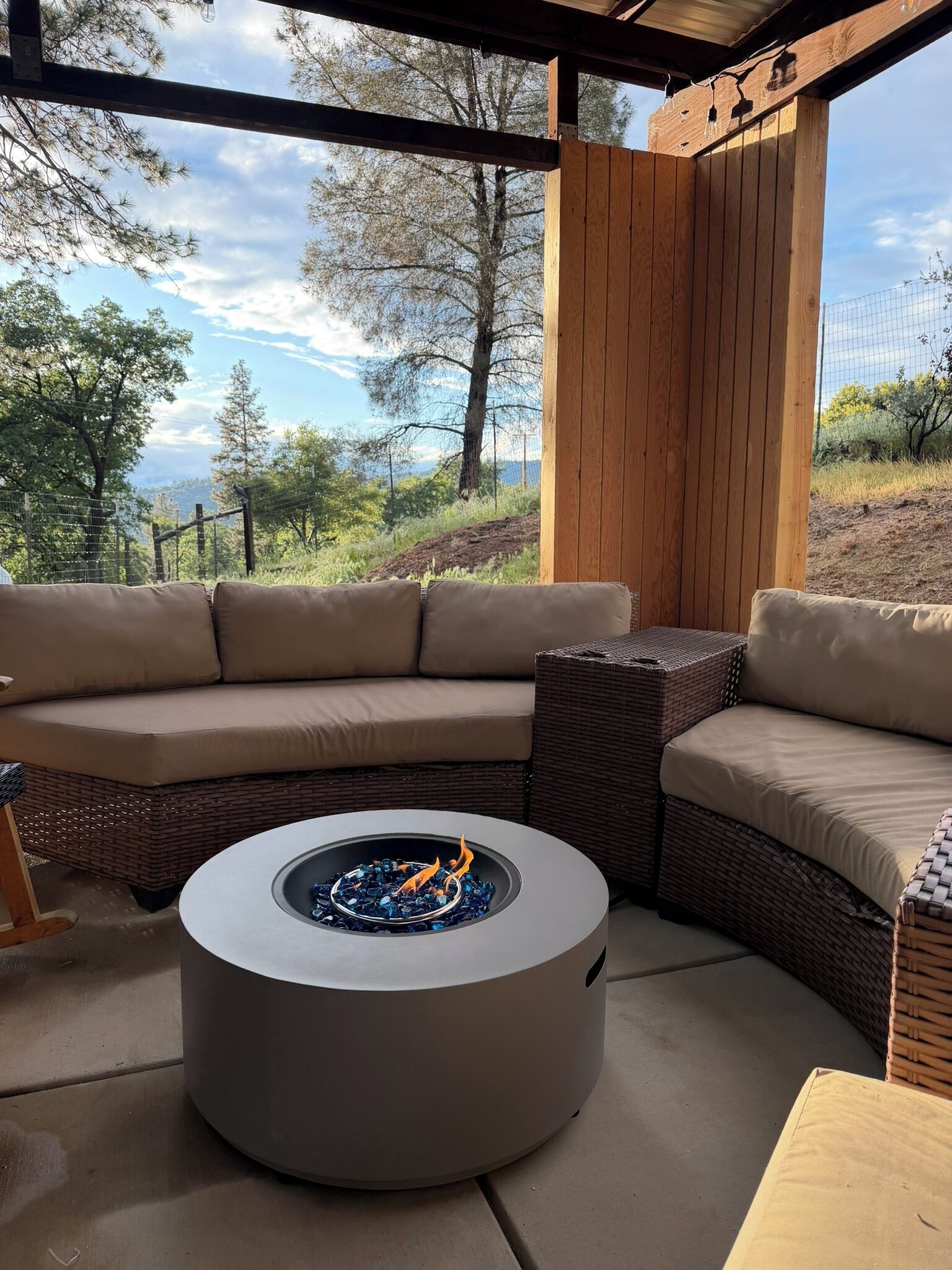 A covered outdoor seating area with a built-in fire pit and a view of the surrounding landscape.