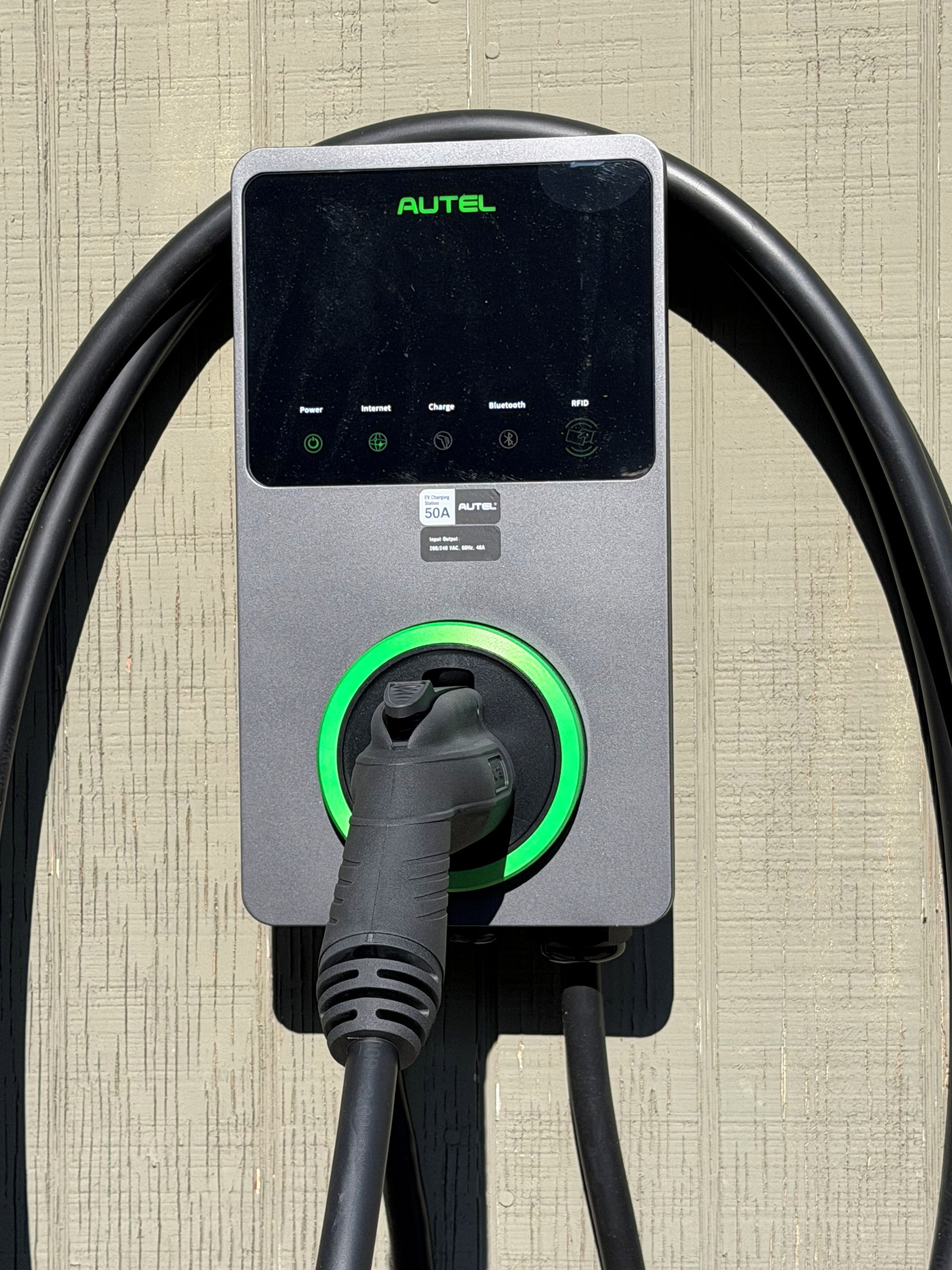 An AUTEL charging station with a display, charging port, and two cables.