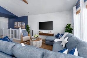 A modern living room with a grey sofa, a round coffee table, and a mounted TV.