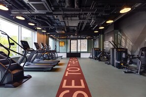 Une salle de sport équipée de tapis de course, de vélos elliptiques et d'appareils de musculation.