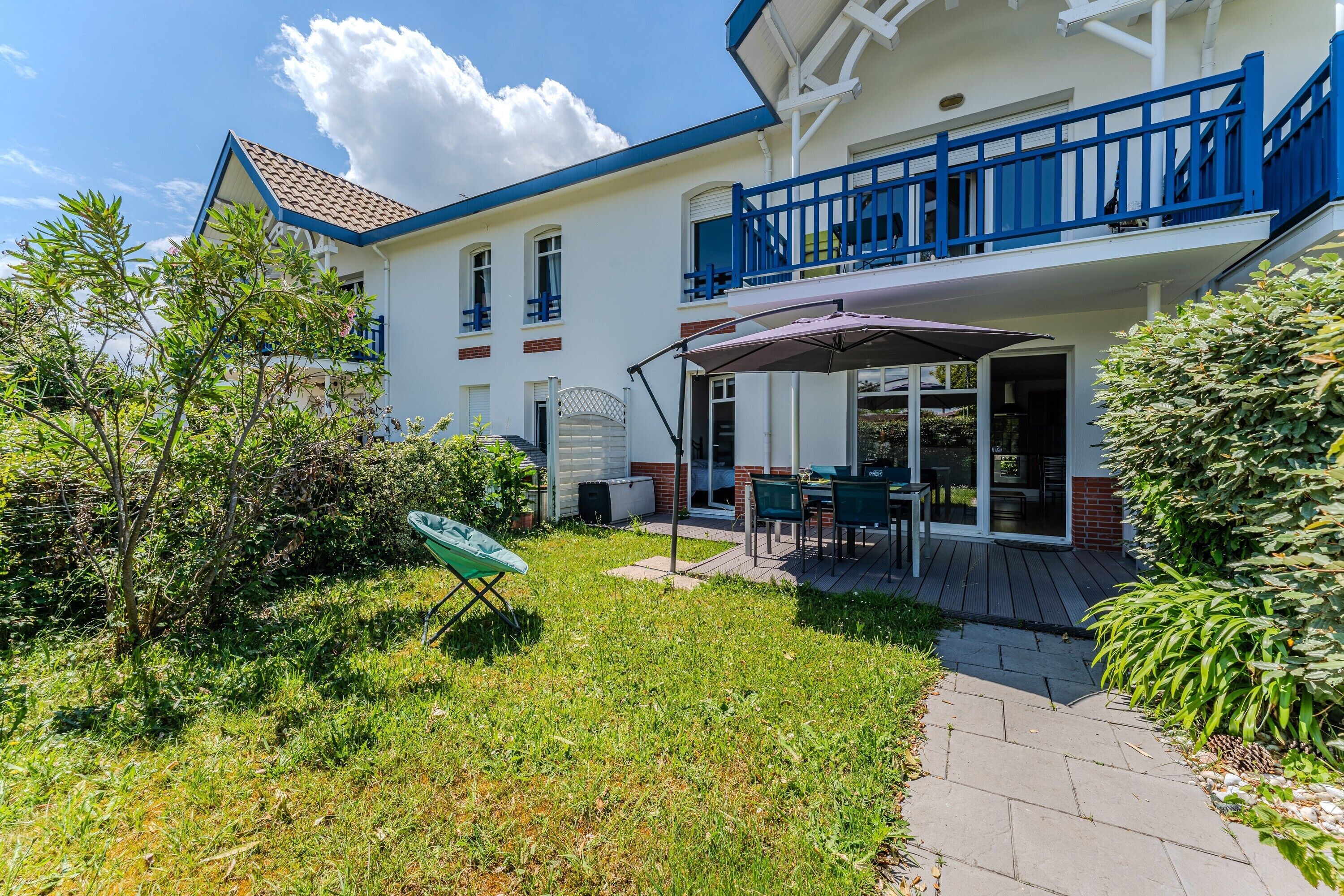 Ein zweistöckiges Gebäude mit Balkon, Terrasse und Garten.