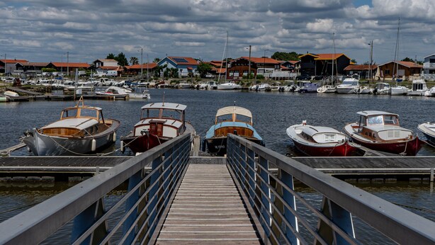 A marina with docked boats, a wooden pier, and buildings with red roofs in the background. - Bel Air with Private Terrace and Garden, 10-Min Walk to Market (La Teste-de-Buch)