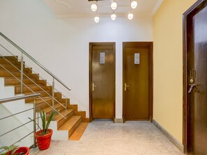 A staircase with metal railings, two wooden doors with numbers, and potted plants. - Townhouse Sushant Lok Phase 1 Hotel Neven (Gurugram)