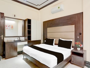 A modern hotel room with a large bed, a built-in wardrobe, a bedside table, and a wall-mounted air conditioning unit. - Townhouse Sushant Lok Phase 1 Hotel Neven (Gurugram)
