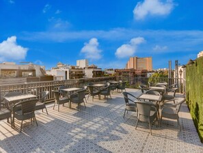 A rooftop terrace with outdoor seating, a cityscape view, and a clear sky. - Townhouse Sushant Lok Phase 1 Hotel Neven (Gurugram)