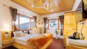 A wooden bedroom with a bed, bedside tables, a ceiling fan, and large windows. - We are one paradise (Mussoorie)