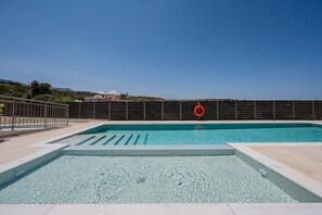 A swimming pool with a lifebuoy, surrounded by a fence, and a view of distant buildings. - Family Luxury Villa in Rethymno Town (Rethymno)