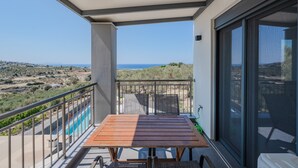 Ein Balkon mit Tisch und Stühlen, ein Pool und Blick auf die Landschaft.