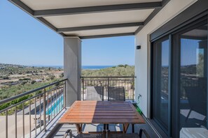 Ein Balkon mit Tisch und Stühlen, ein Pool und Blick auf die Landschaft.