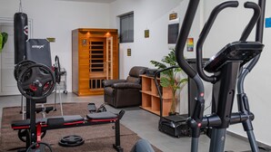 Ein Heimfitnessraum mit Laufband, Ergometer und einer Gewichtbank.