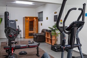 Ein Heimfitnessraum mit Laufband, Ergometer und einer Gewichtbank.