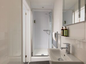 Ein modernes Badezimmer mit Duschkabine aus Glas, einem weißen Waschbecken und einem Spiegel darüber.
