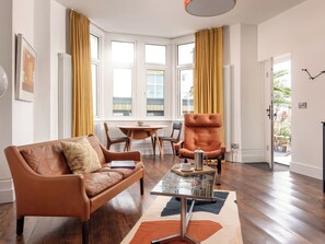 A modern living room with a leather sofa, a tufted armchair, a coffee table, and a dining area with a table and chairs. - Jimi Hendrix by Interhome (Falmouth)