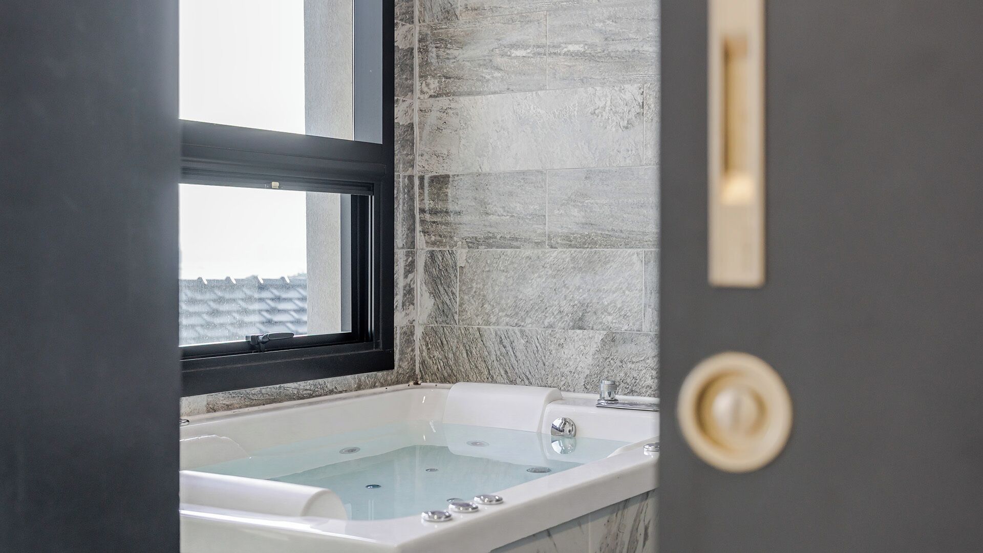 A bathroom with a bathtub, a window, and a door.