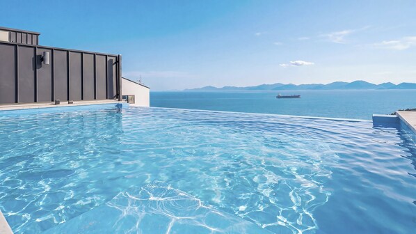 Una piscina infinita con vistas despejadas al mar y montañas lejanas.