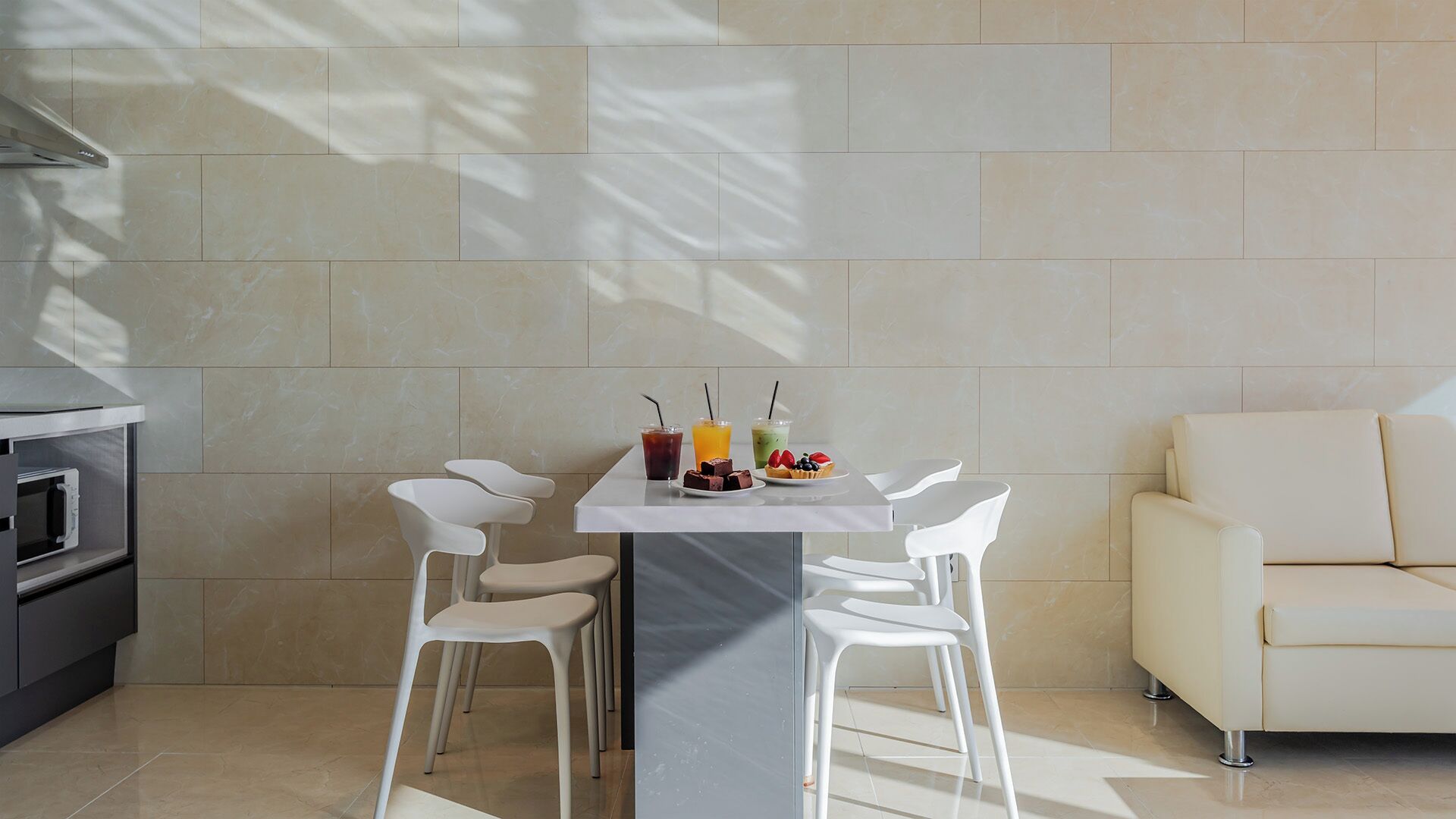 A modern kitchen with a dining table, chairs, and a sofa.