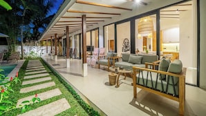Un área lounge moderna al aire libre con piscina, asientos y vistas al interior.