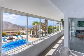 Ein Balkon mit Pool, Liegestühlen und Blick auf die Landschaft.