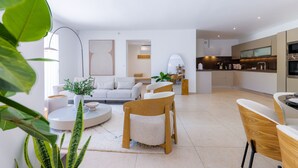 Una sala de estar moderna con sofá, sillones, una mesa de centro y un comedor con mesa y sillas.