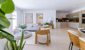 Ein modernes Wohnzimmer mit einer Couch, Sesseln, einem Couchtisch und einem Essbereich mit Tisch und Stühlen.