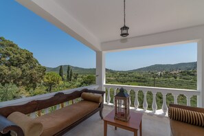 Uma varanda com um banco de madeira, uma mesa pequena e um candeeiro.